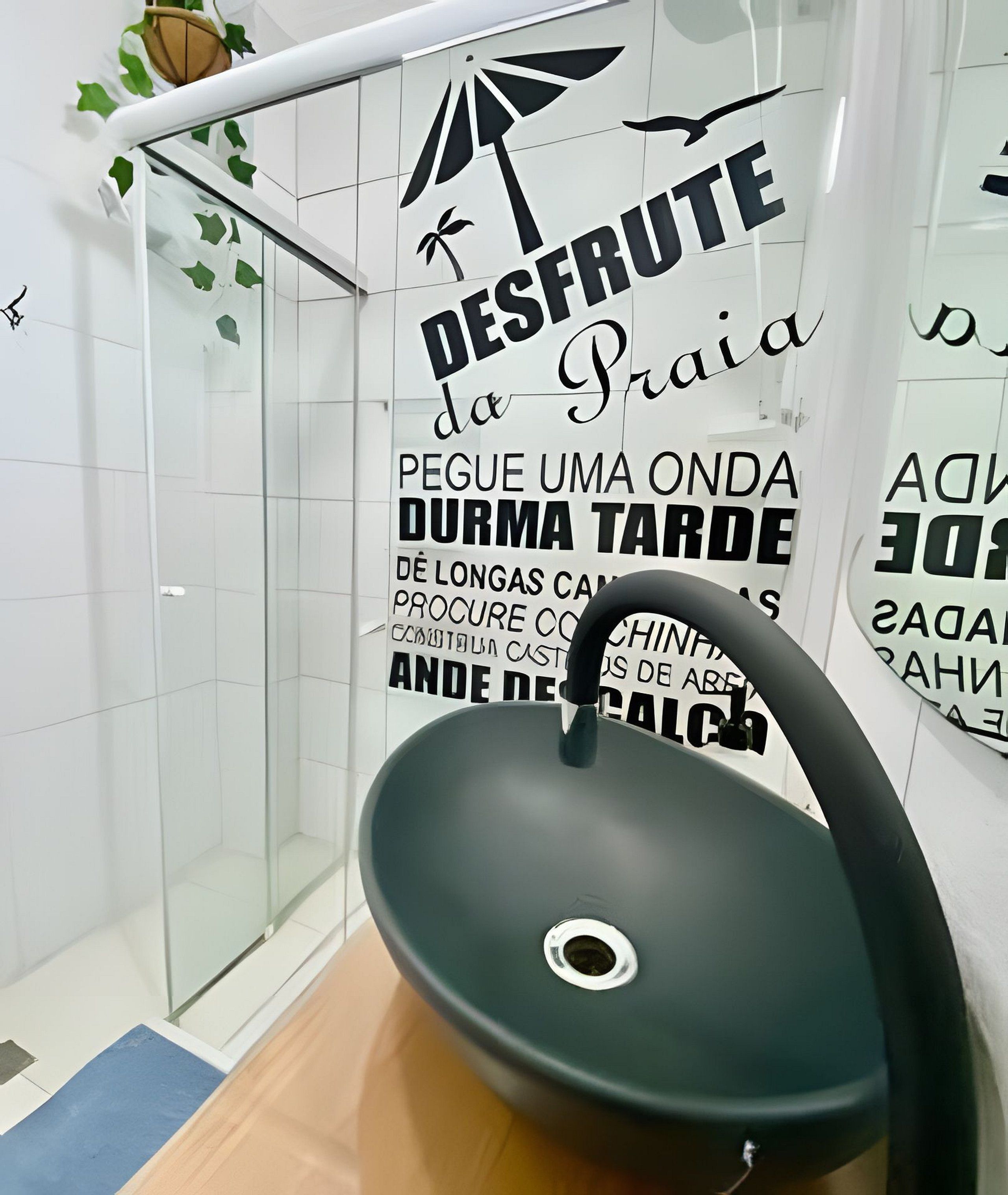 Un gimnasio con una bicicleta estática negra, cabina de ducha de vidrio y decoración mural motivacional.