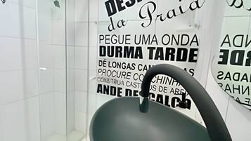 Un gimnasio con una bicicleta estática negra, cabina de ducha de vidrio y decoración mural motivacional.