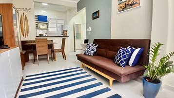 Una sala de estar moderna con un sofá marrón, alfombra a rayas y una planta en maceta.