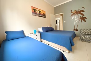 Un dormitorio con dos camas, una mesita de noche, un cuadro y un mural en la pared.