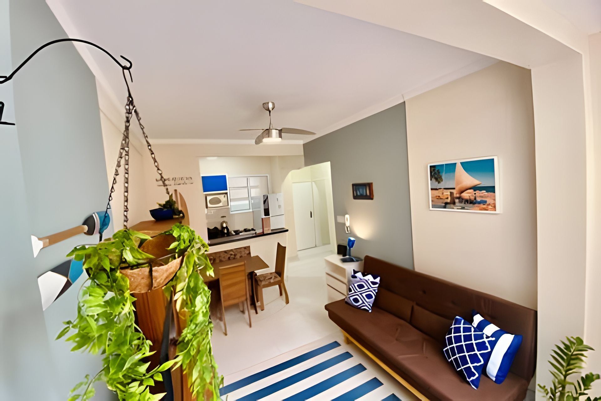 Una sala de estar moderna con un sofá marrón, una zona de comedor y una cocina al fondo.