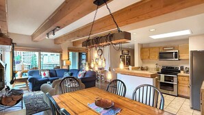 Amplia sala de estar con una mesa de comedor de madera, un sofá y una cocina equipada con electrodomésticos modernos.