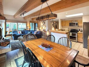 Ein geräumiger Wohnbereich mit Esstisch aus Holz, einer Couch und einer Küche mit modernen Geräten.