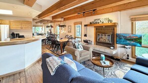 Un espacio habitable espacioso con chimenea, televisor y comedor con mobiliario de madera.