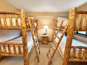A room with bunk beds made of wood, a small bedside table with a lamp, and a window. - New Listing - Plaza 638— 2BR Walk to Crested Butte Lifts (Crested Butte)