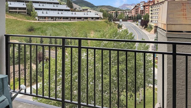 Un balcón con vista a una carretera, edificios y un paisaje montañoso.