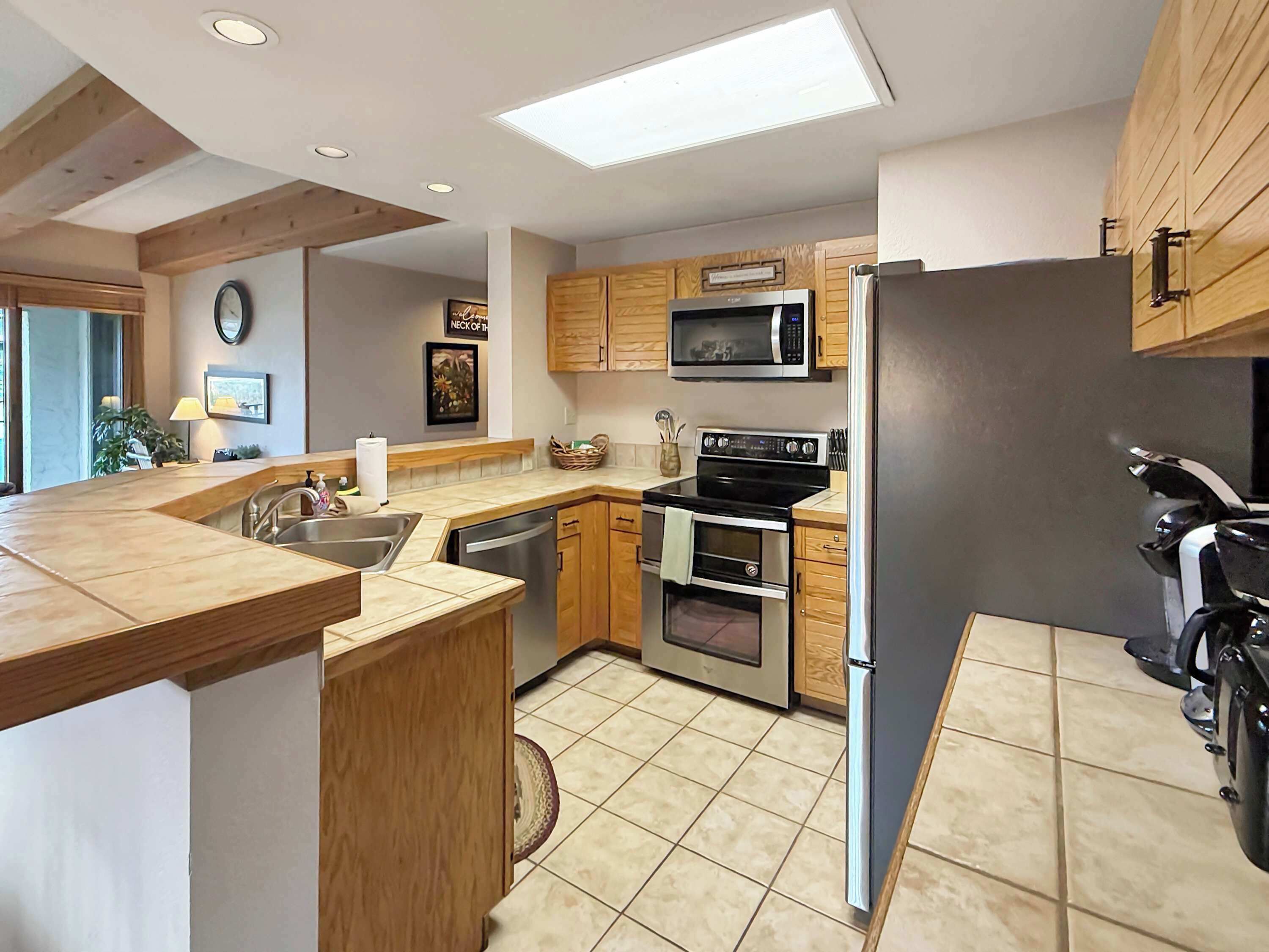 A modern kitchen with wooden cabinets, a microwave, an oven, and a refrigerator.