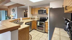Una cocina moderna con armarios de madera, microondas, horno y refrigerador.