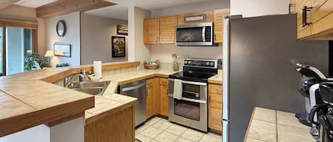A modern kitchen with wooden cabinets, a microwave, an oven, and a refrigerator.