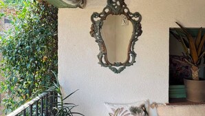 A balcony with a potted plant, a decorative mirror, and a cushioned bench. - L'Oustalet Maelvi – In the medieval heart of Grimaud, 50 meters from the castle and the church (Grimaud)