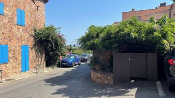 Een smalle straat met stenen gebouwen, geparkeerde auto's en begroening.