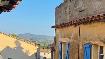 Une ruelle étroite, bordée de bâtiments des deux côtés, avec un escalier bien visible et une vue dégagée sur le paysage environnant.