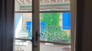 A door with a view of an outdoor patio area, including a table and chairs. - L'Oustalet Maelvi – In the medieval heart of Grimaud, 50 meters from the castle and the church (Grimaud)