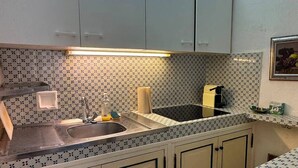 A kitchen with a tiled backsplash, a sink, cabinets, and a countertop. - L'Oustalet Maelvi – In the medieval heart of Grimaud, 50 meters from the castle and the church (Grimaud)