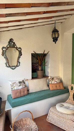 A cozy seating area with a bench, cushions, a mirror, a potted plant, and a hanging lantern.