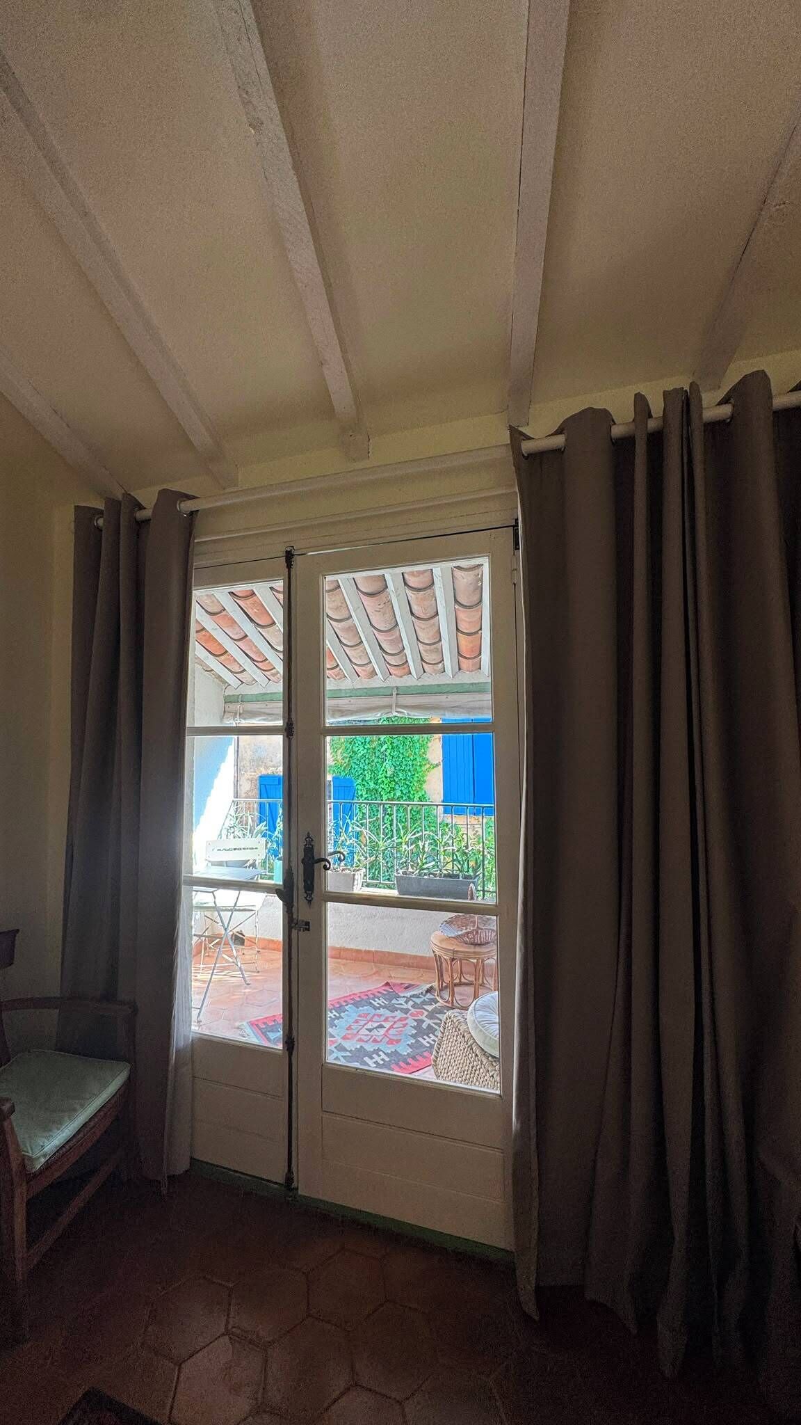 A room with a door leading to an outdoor area, a chair, and a tiled floor.