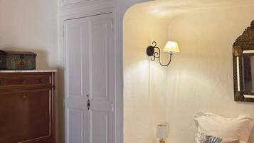 Une chambre d’hôtel avec un lit, une commode, une table de chevet avec une lampe et un miroir au mur.