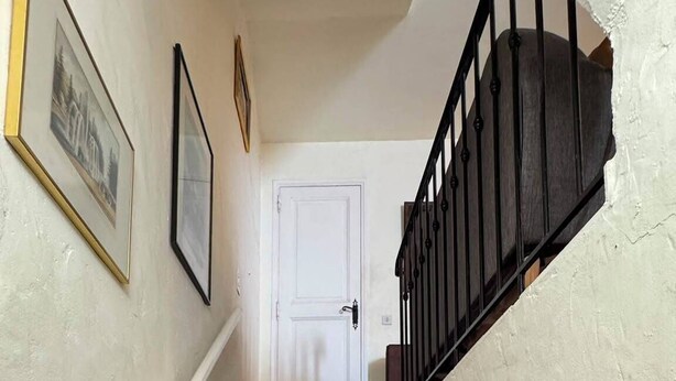A staircase with a white door at the top, a handrail on the left, and a black railing on the right. - L'Oustalet Maelvi – In the medieval heart of Grimaud, 50 meters from the castle and the church (Grimaud)