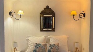 A neatly made bed with two pillows, a mirror, and two wall-mounted lamps. - L'Oustalet Maelvi – In the medieval heart of Grimaud, 50 meters from the castle and the church (Grimaud)