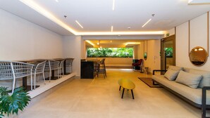 Un interior moderno con mostrador de recepción, zona de estar y vistas al verdor.