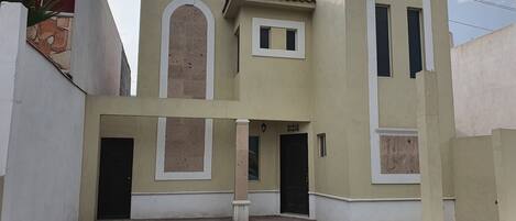 A two-story building with a central courtyard, a flat roof, and a small garden area.