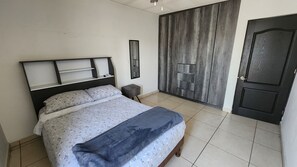 A bedroom with a bed, a nightstand, a wardrobe, and a door.