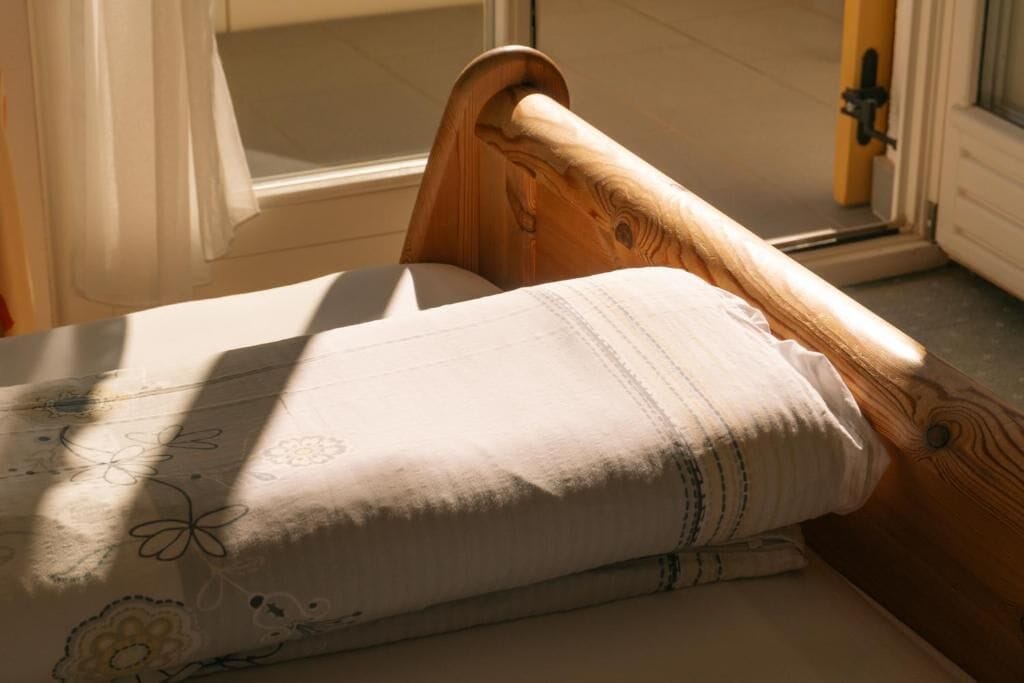 A wooden bed with a white mattress and a floral-patterned blanket.