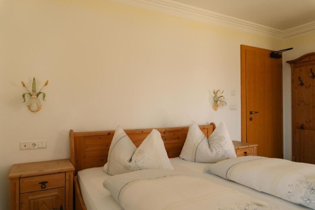 Un dormitorio con una cama de madera, dos mesitas de noche, un armario de madera y apliques de pared.