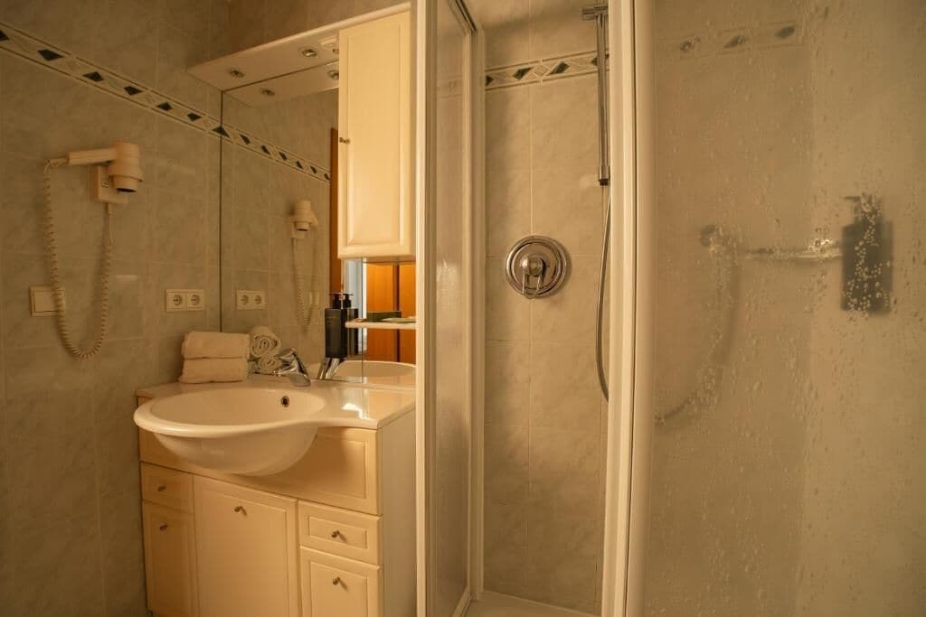 A bathroom with a sink, mirror, and shower.