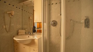 A bathroom with a sink, mirror, and shower.