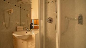 A bathroom with a sink, mirror, and shower.
