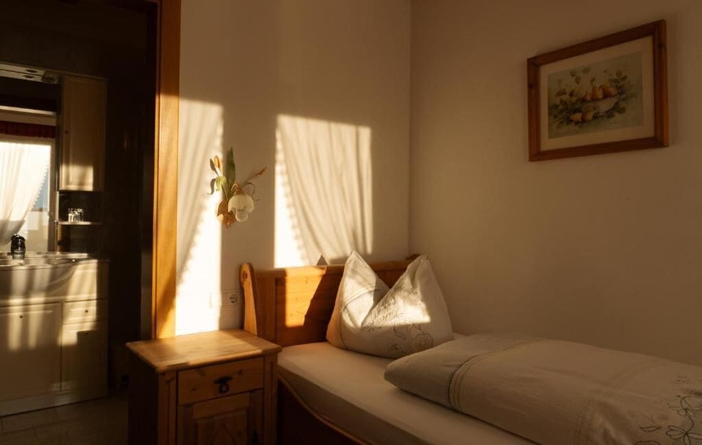 A bedroom with a bed, a nightstand, a wooden cabinet, and a window with curtains.