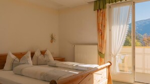 A bedroom with a wooden bed, a radiator, and a view of the outdoors through a sliding glass door.