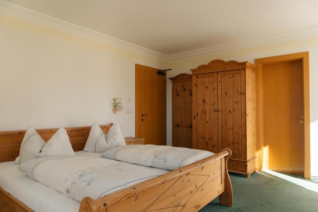 Ein Schlafzimmer mit einem hölzernen Bett, einem Kleiderschrank und einer Tür zu einem anderen Raum.