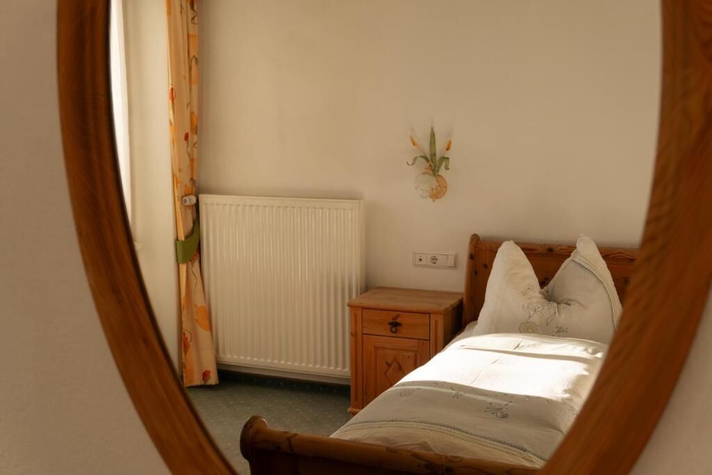 Un dormitorio con una cama, una mesita de noche, una planta en la pared y un radiador.