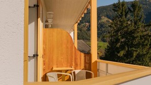 A balcony with a wooden railing, a small table, and two chairs.