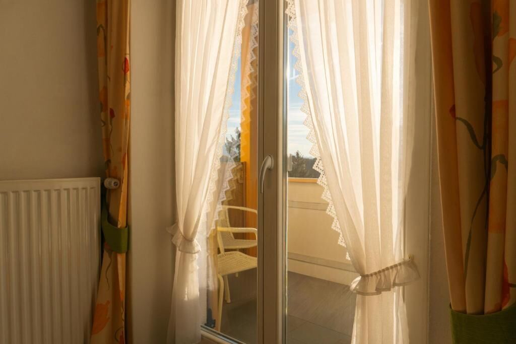 Una habitación con puerta de vidrio corredera, un radiador blanco y una silla afuera.