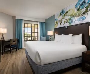Una habitación de hotel con una cama grande, un escritorio y una ventana con cortinas.