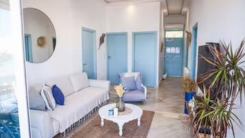 A modern living room with a white sofa, a round coffee table, and a blue chair. There are two blue doors in the background.