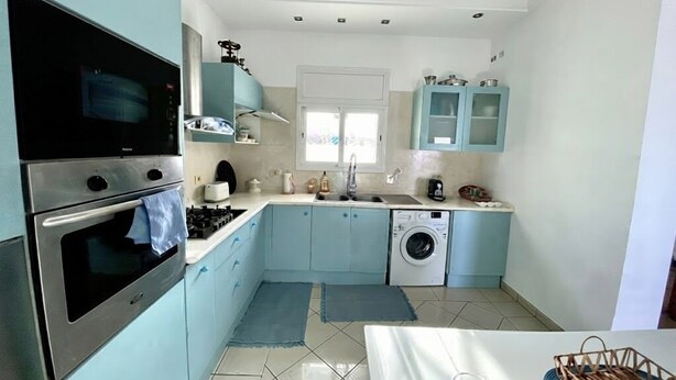 Cocina compacta equipada con microondas, horno, pileta y lavadora.