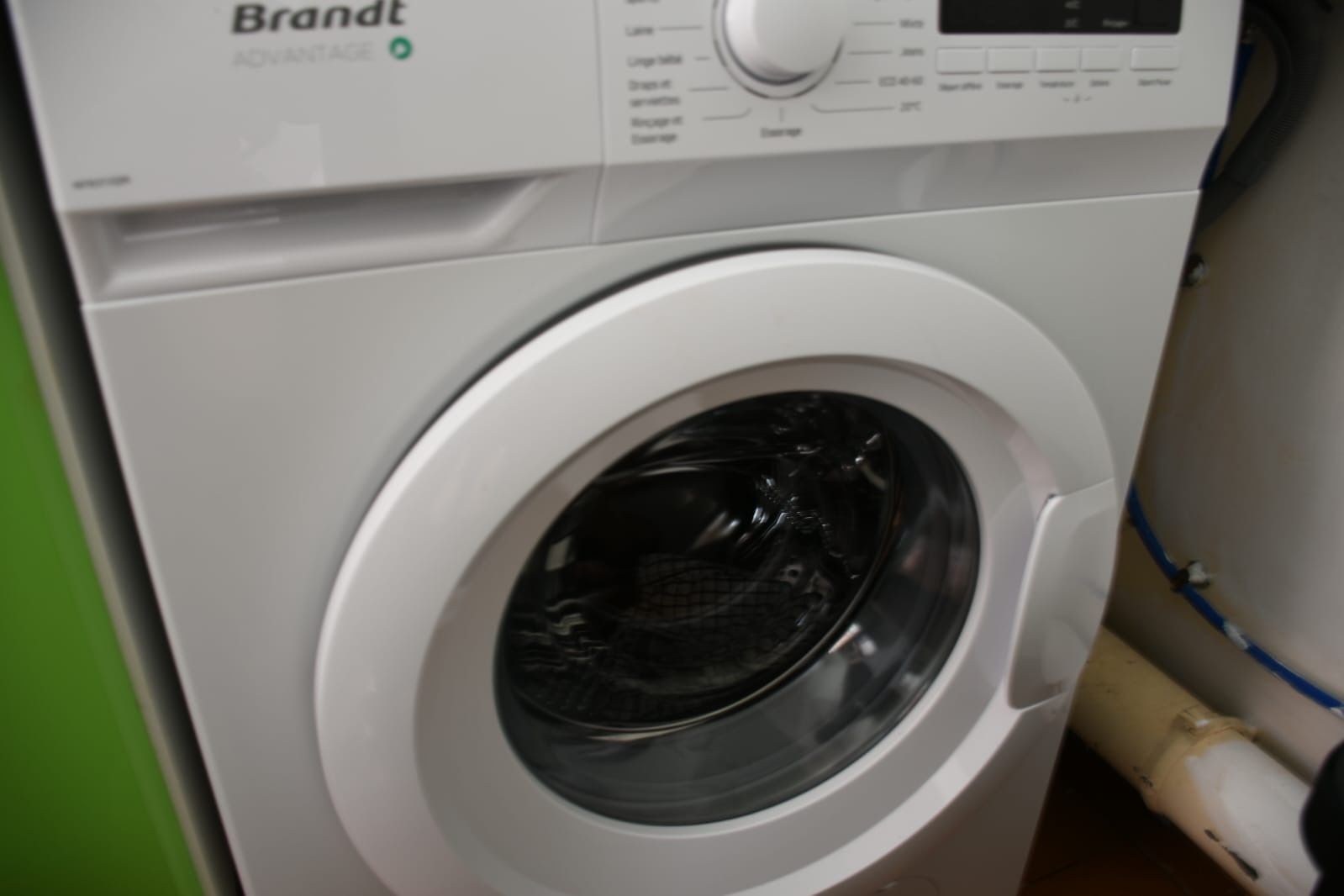 Een voor aanzicht van een Brandt wasmachine, met een bedieningspaneel en een glazen deur.
