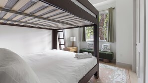 A bunk bed room with a wooden ceiling, a bedside table with a lamp, a window with curtains, and a motivational pillow. - Tremendous 9-bedroom Luxury Compound - Two Pools & Two Houses (Austin)