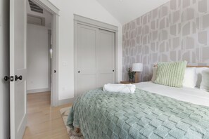 A bedroom with a bed, a nightstand, a lamp, and a wall with a geometric pattern. - Tremendous 9-bedroom Luxury Compound - Two Pools & Two Houses (Austin)