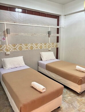 Habitación de hotel con dos camas, pared de azulejos, un borde estampado y una pared blanca con un cartel de no fumar.