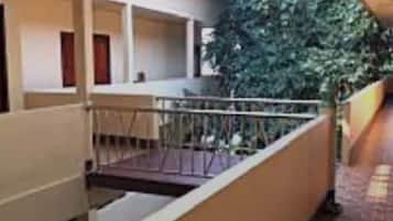 A corridor with a metal railing, a staircase, and a green plant.