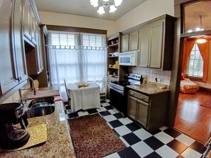 A kitchen with a checkered floor, a dining table, and a refrigerator. - Historic Double Shotgun Home in Spanish Town, Downtown Baton Rouge (Baton Rouge)