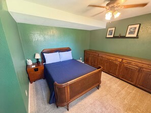 A bedroom with a bed, nightstand, dresser, and ceiling fan.
