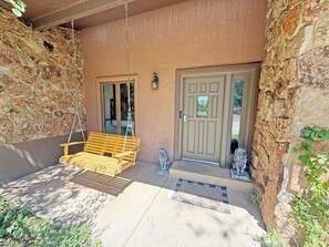 A stone exterior with a wooden swing, a door, and a welcome mat.
