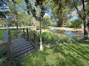 A wooden bench, a lamp post, and a pond with a boat.