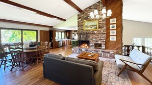 A spacious living room with a fireplace, wooden flooring, and a dining area with wooden furniture.